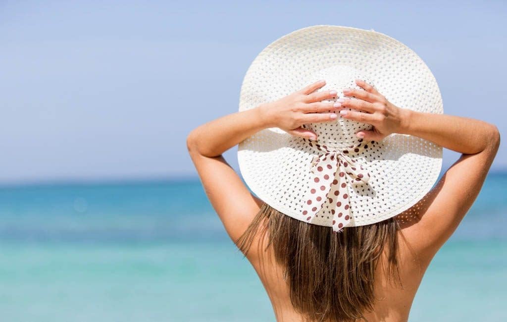 Girl wearing a sun hat looking out over the ocean. This complete beach packing guide includes everything you need for your next tropical vacation. Plus, suggestions on products you'll love on your travels! And for more travel tips follow The Scenic Suitcase on Pinterest!