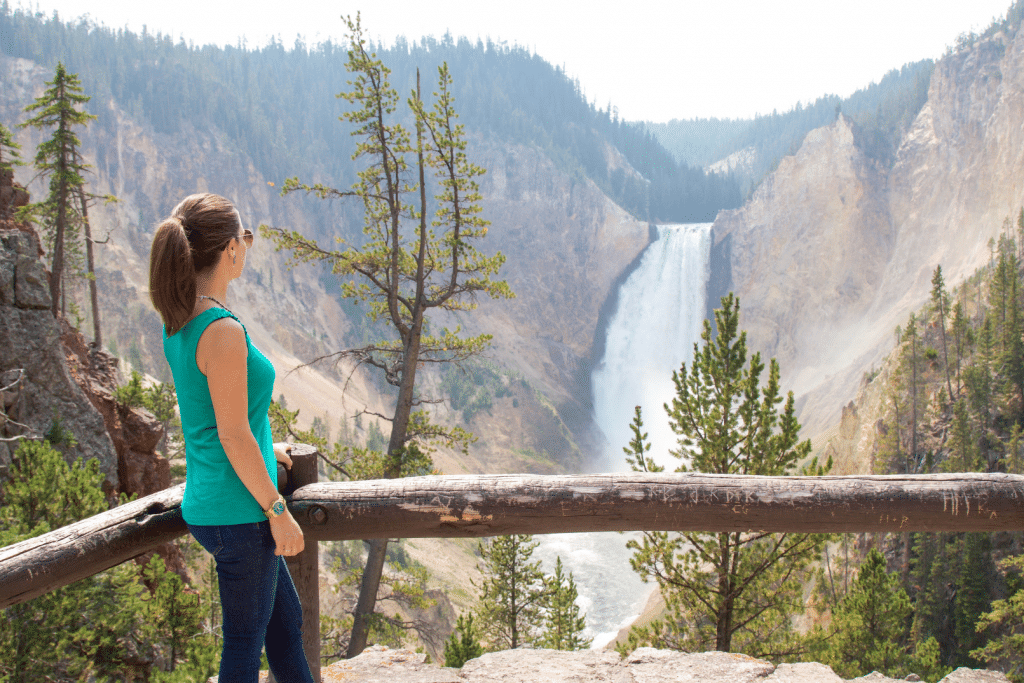 Girl looking at Lower Falls in Yellowstone. Discover the 10 best U.S. National Parks you should definitely add to your bucket list.