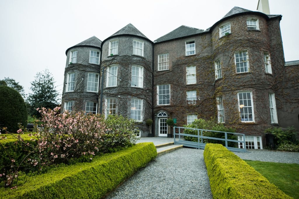 A stone facade of a hotel surrounded by greenery.