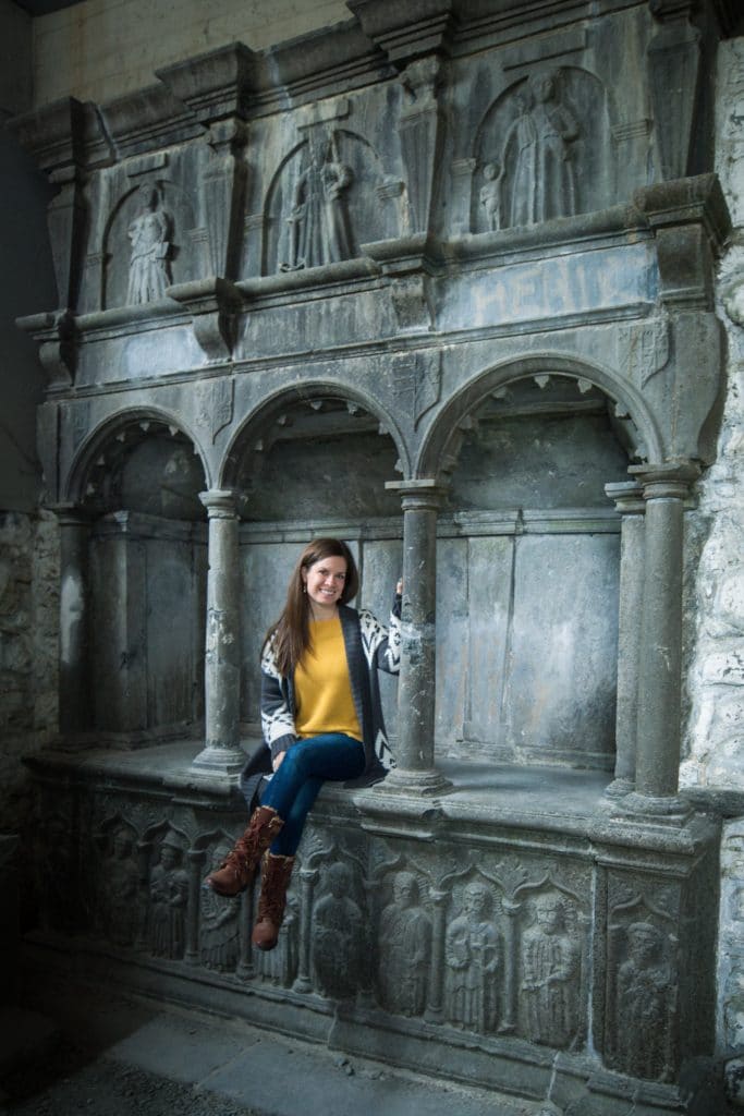 A girl in a yellow sweater sitting on a stone ledge.