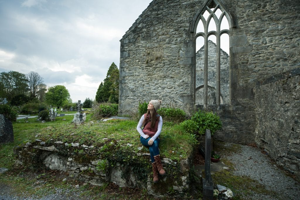A girl sitting along a stone ledge outside an abandon abbey. #muckrossabbey