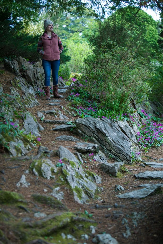 A girl standing along a stone path through a hilly garden. #muckrosshouse #killarney