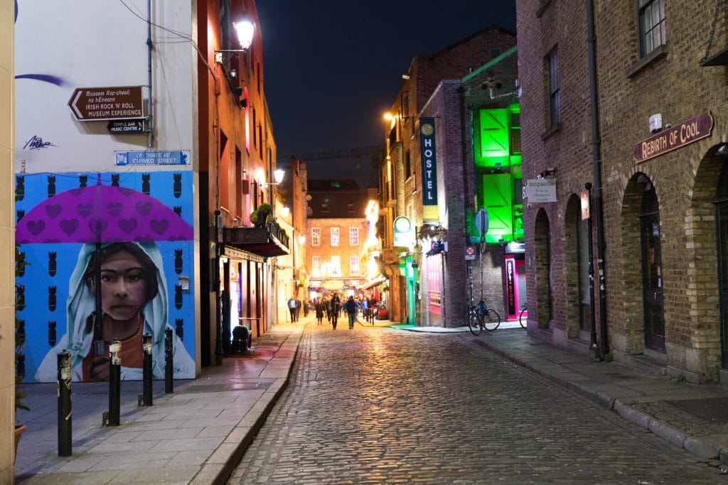 A cobblestone street in Dublin lit up at night.
