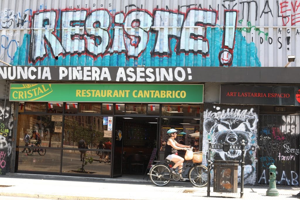 A woman riding a bike past graffiti in Santiago, Chile. #graffiti #santiago 