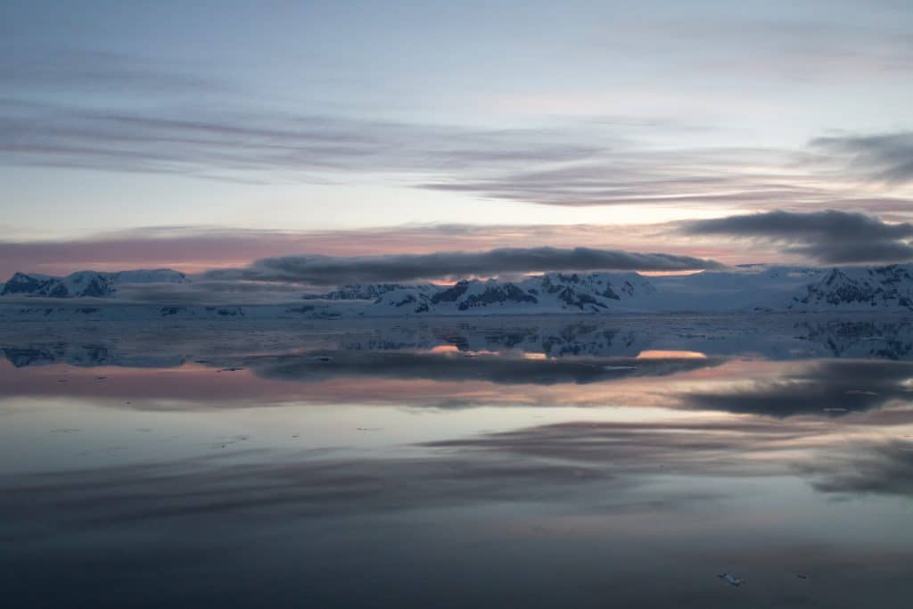 Sunset clouds and mountains reflected in the ocean in Antarctica. #antarctica