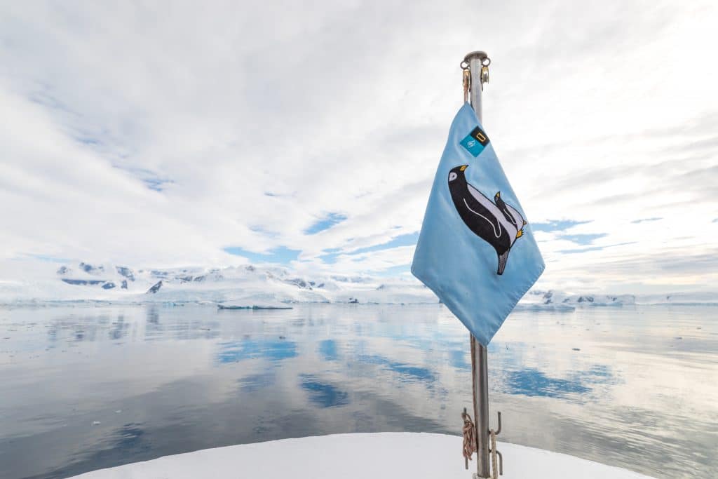 A penguin flag on a ship with reflective water in Antarctica. #antarctica