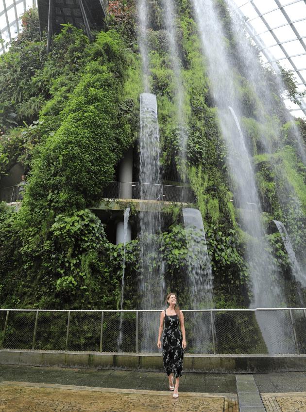 A girl walking in front of a green indoor forest with waterfalls in Singapore. One of the picture perfect moments of 2019. #singapore 