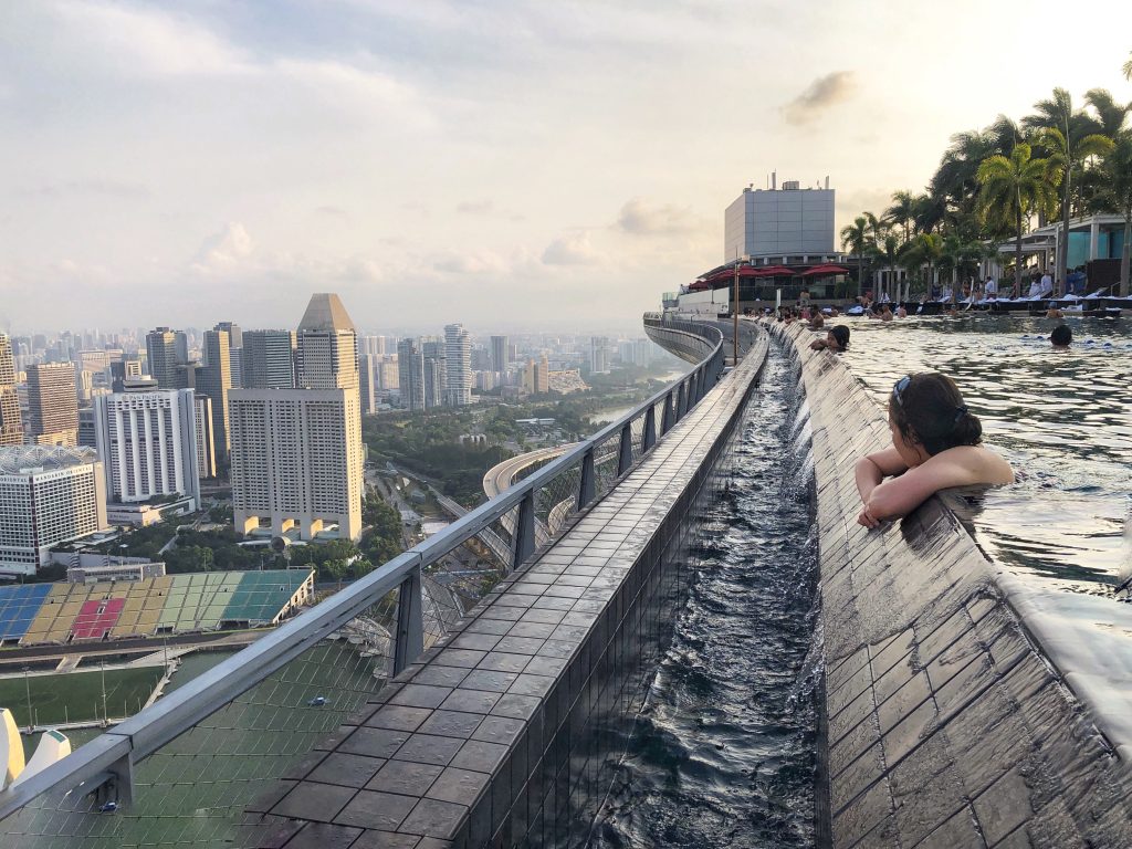 A girl hanging over the edge of the Marina Bay Sands infinity pool looking out over the horizon. One of the many reasons to visit Singapore. #singapore #marinabaysands