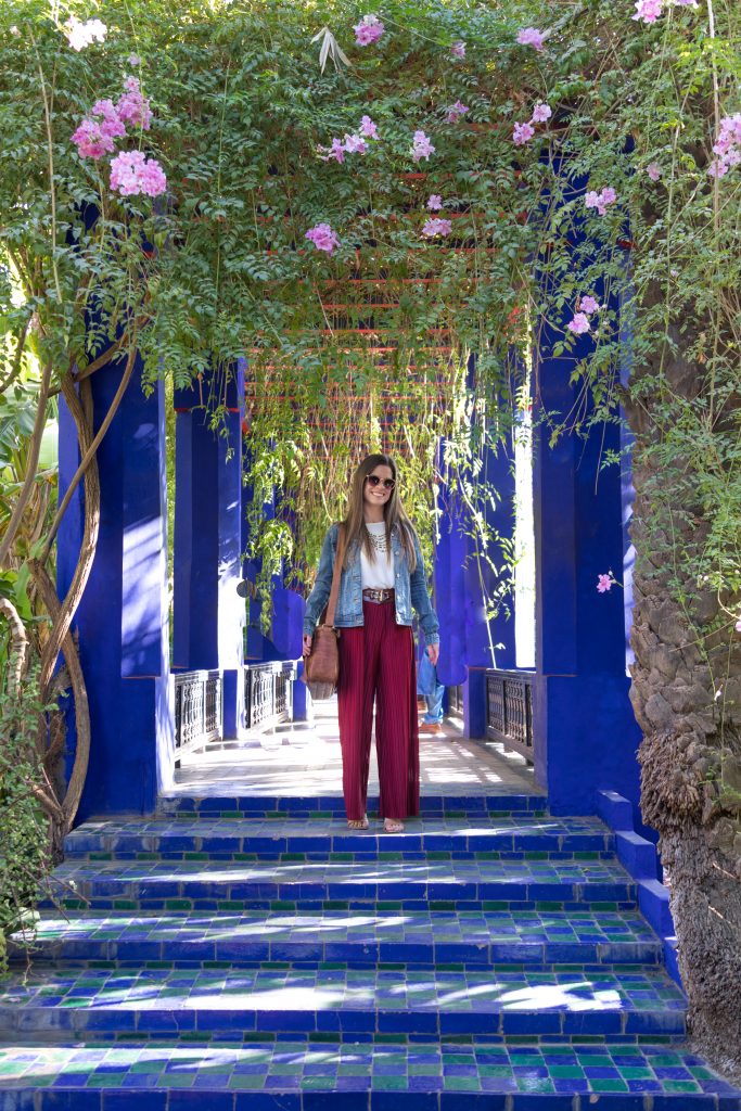 A girl standing at the top of a blue tile staircase surrounded by floral vines in Jardin Majorelle. #marrakesh #jardinmajorelle