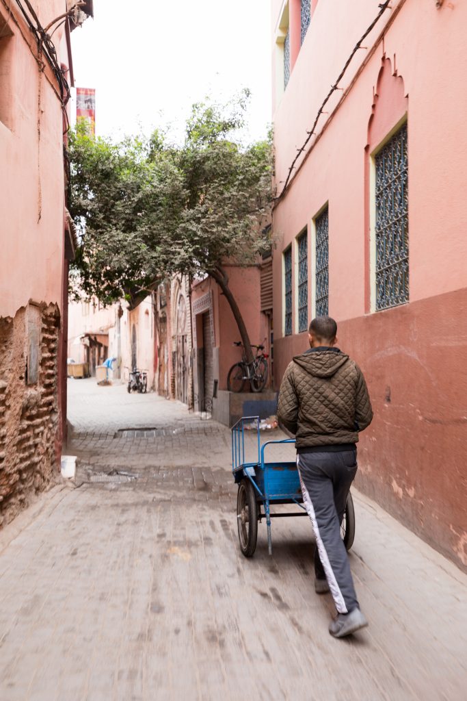A man pushing a blue cart through the cobblestone streets of the Marrakesh medina. #marrakesh #medina
