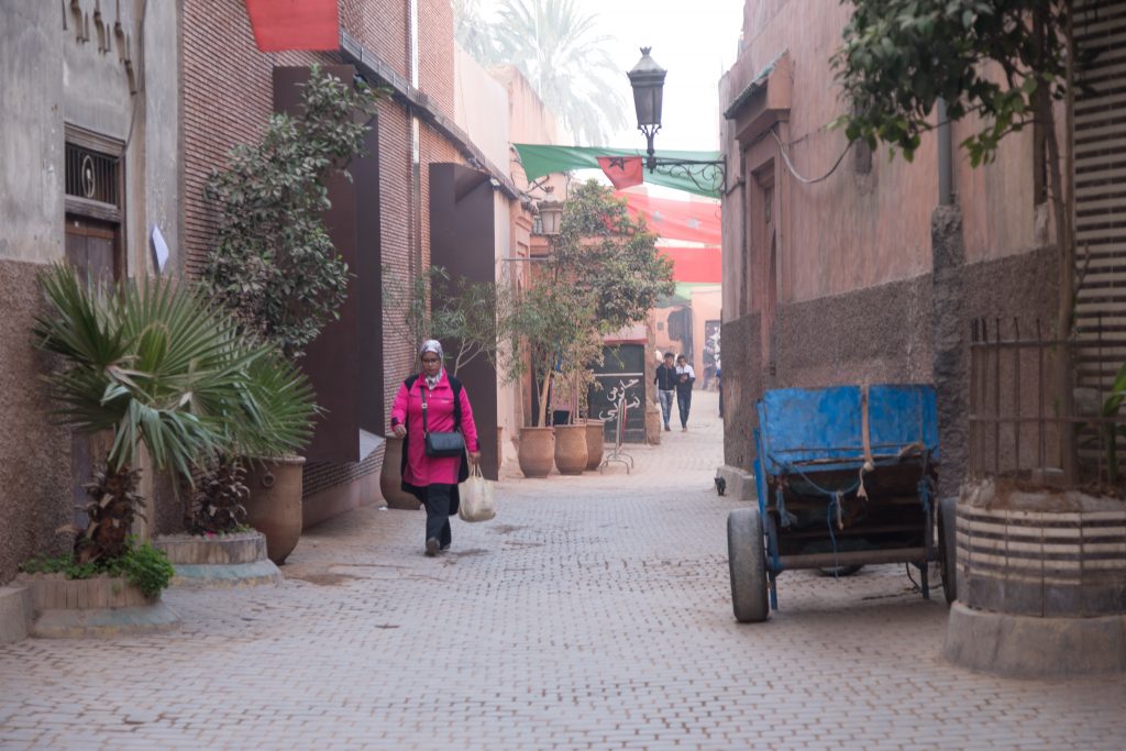 A woman in pink walking through the cobblestone streets of the Marrakesh medina. #marrakesh #medina