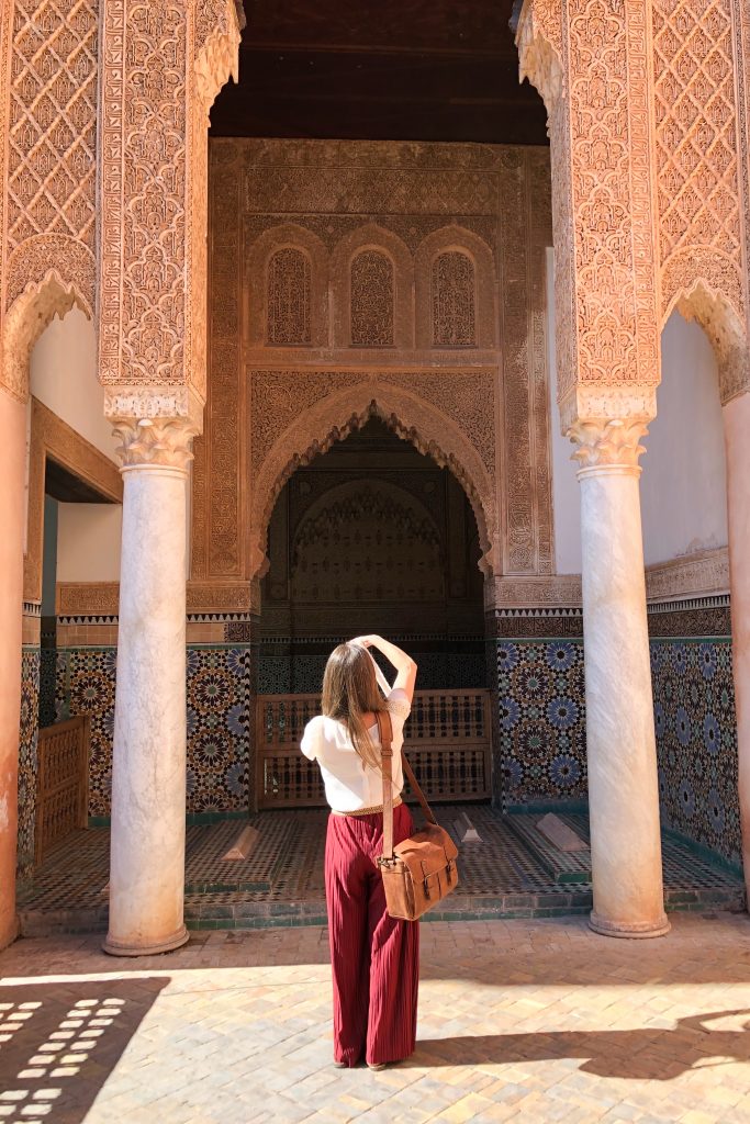 A girl taking a photograph of one of the Saaddiens Tombs in Marrakesh. Discover the many alluring reasons to visit Marrakesh, Morocco. From must-see sights to can't-miss experiences, here's the very best of Marrakesh! #marrakesh #saaddienstombs