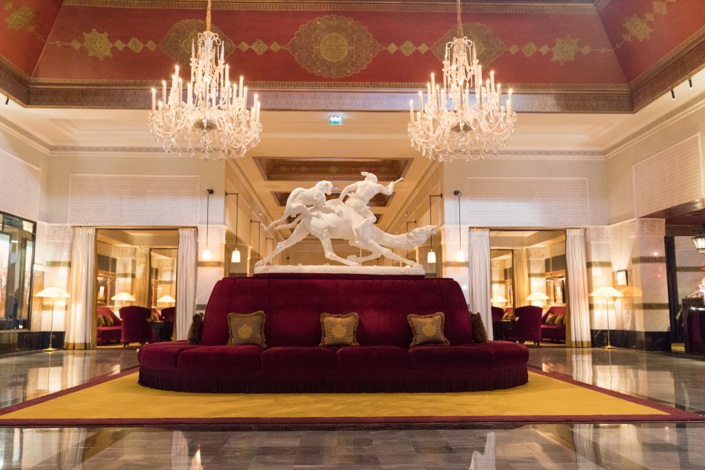 Two large crystal chandeliers and a red couch inside the lobby of La Mamounia. #marrakesh #lamamounia