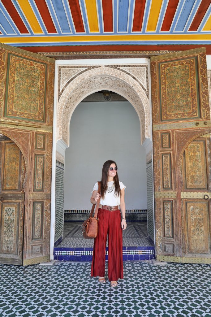 A girl walking through an elaborately decorated Moroccan doorway. Discover the many alluring reasons to visit Marrakesh, Morocco. From must-see sights to can't-miss experiences, here's the very best of Marrakesh! #marrakesh #marrakech