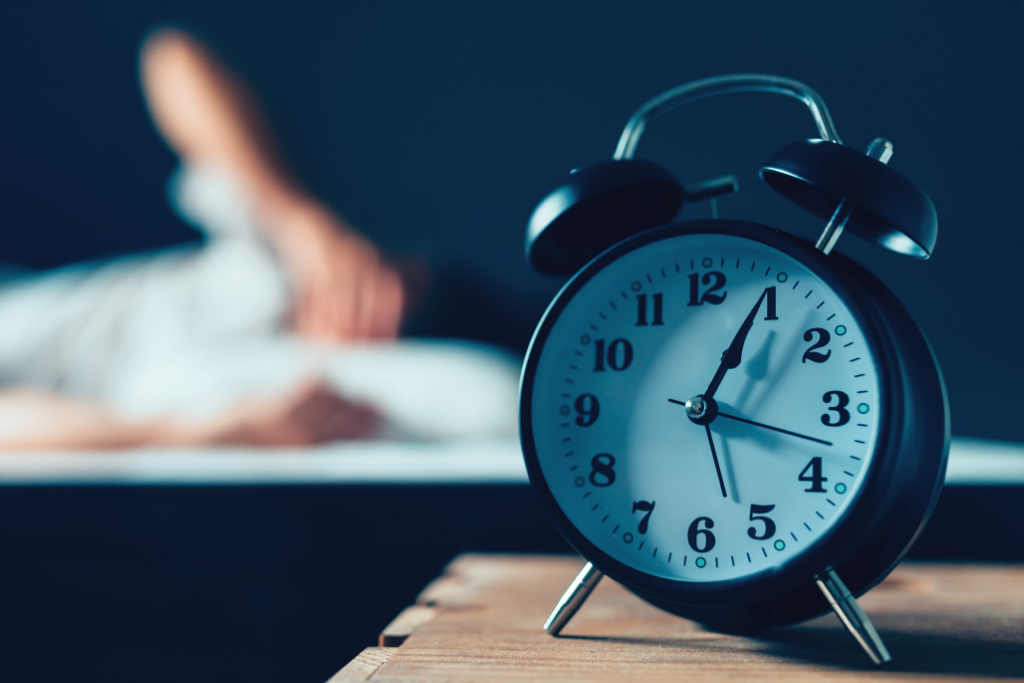 Person sleeping behind an alarm clock.