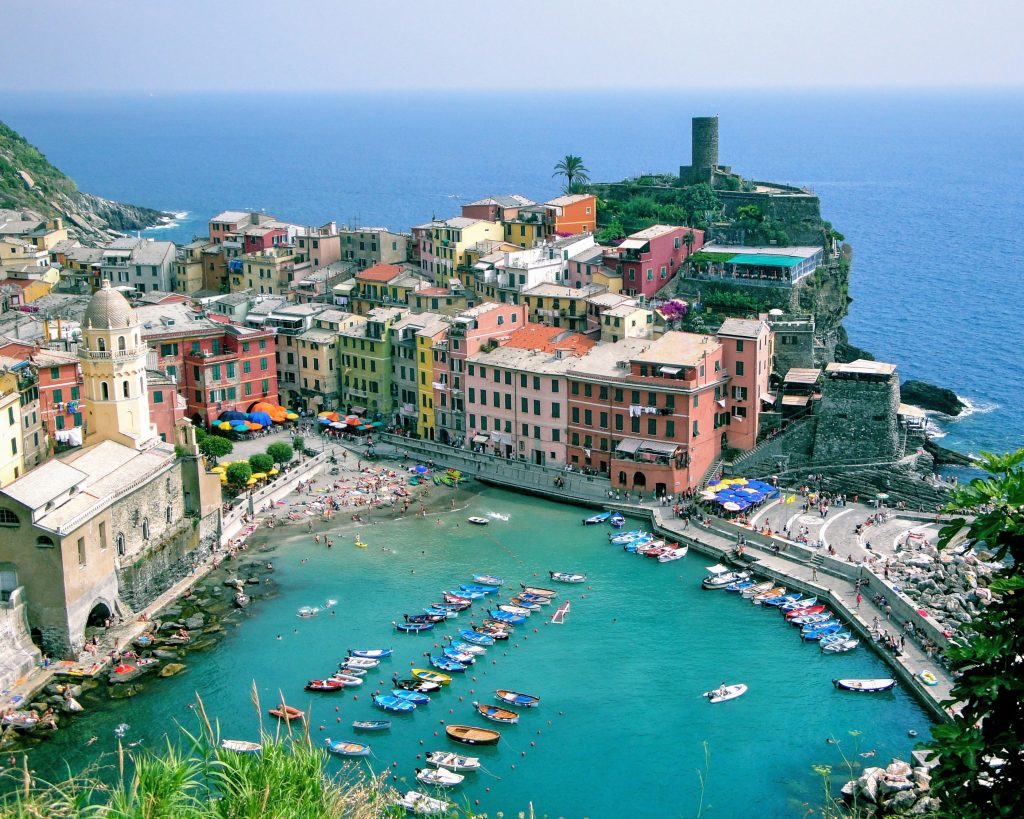 A bay with colorful building facades in Vernazza, Italy. Hiking around Cinque Terre is one of the most breathtaking bucket list experiences you can have. #bucketlistexperiences