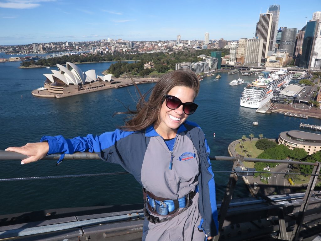 A girl on top of the Sydney Harbour Bridge. Climbing the bridge is one of the best bucket list experiences anyone can have! #bucketlistexperiences