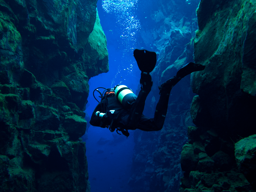 A diver swimming between the tectonic plates of the Silfra Fissure.