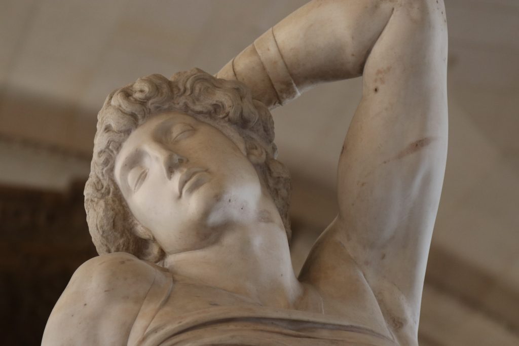 A sculpture of a man with his hand in his hair inside the Louvre.