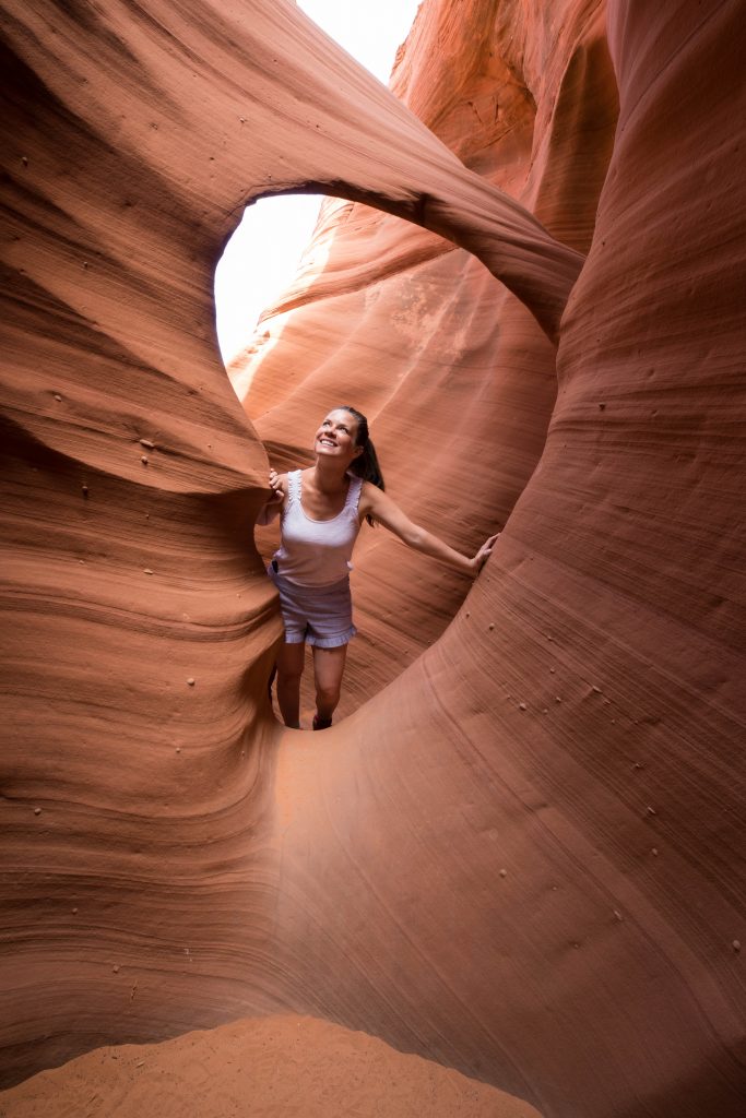 A girl looking up inside a slot canyon arch.