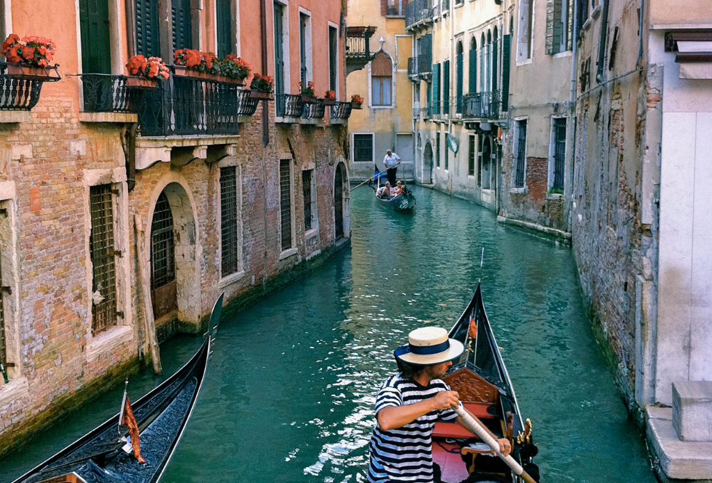 A gondolier making his way through a canal. Venice is one of the most stunning bucket list destinations in the world. #bucketlistdestinations