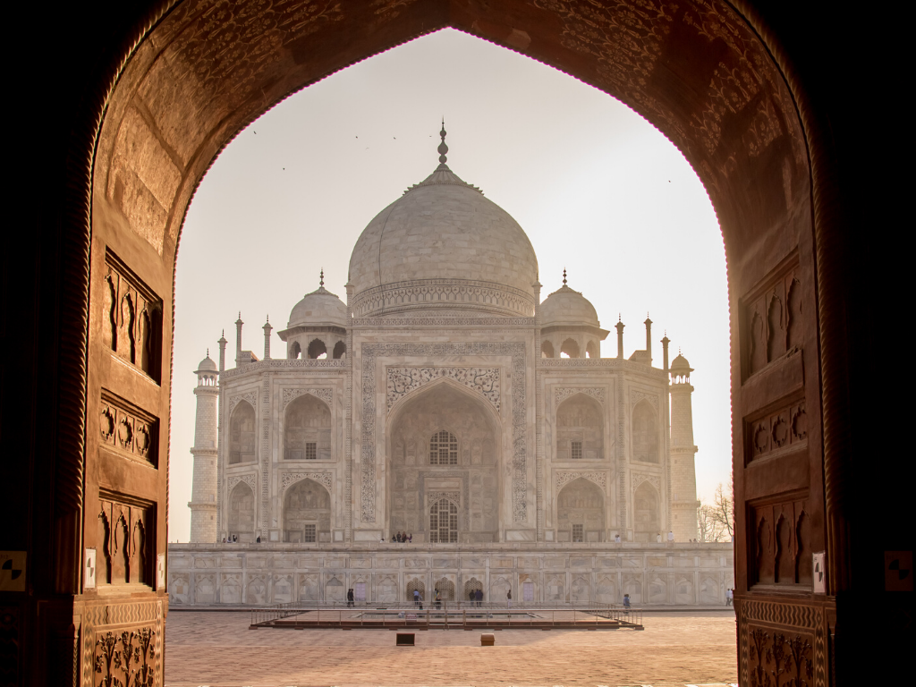 The Taj Mahal fron the archway of a nearby building. It is one of the most stunning bucket list destinations in the world.
