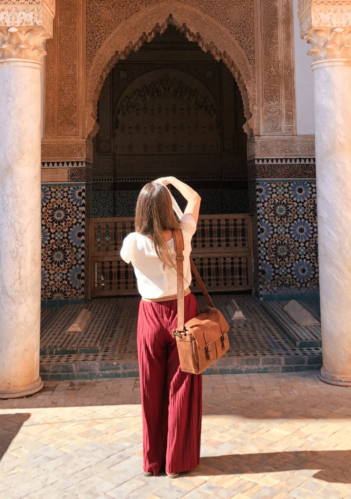 A girl photographing an archway with a brown leather camera bag.