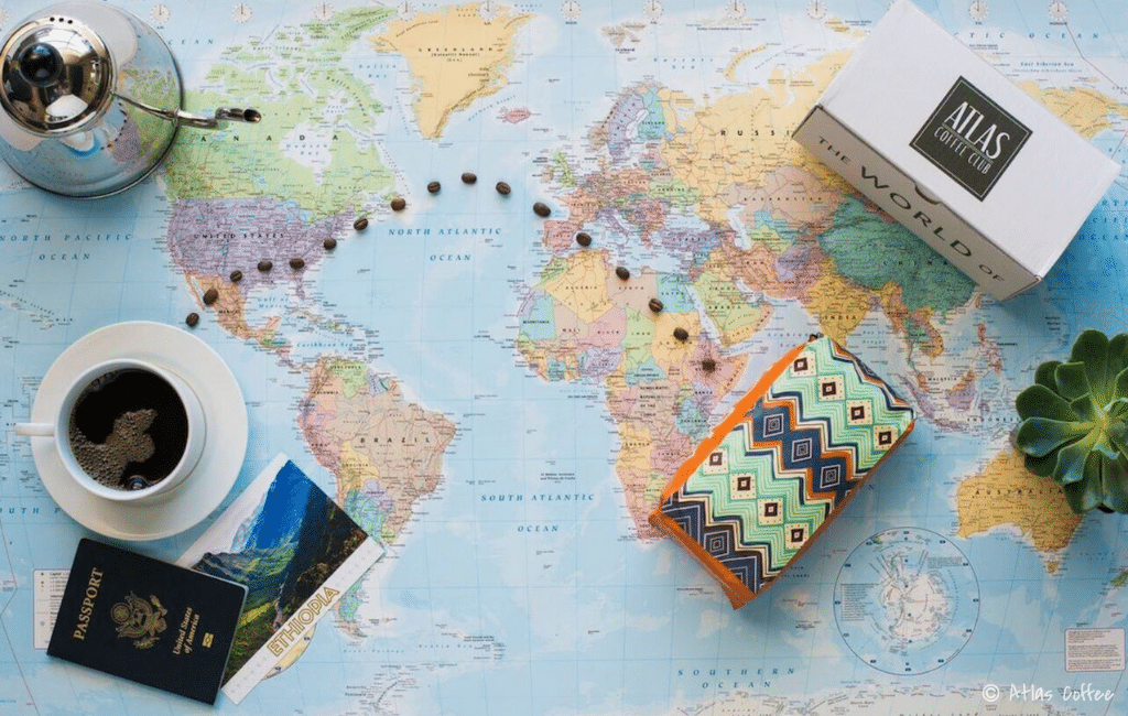 Atlas Coffee bag with beans laid out over a world map. Discover 8 of the most incredible subscription boxes for travelers to help fuel your wanderlust. Buy them for yourself or as awesome gifts!