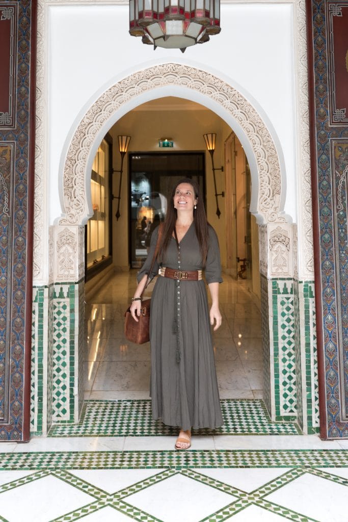 A girl in a green dress and brown belt walking through a doorway in Marrakesh.