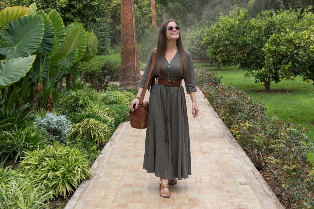 A girl in a green dress walking through a tropical garden pathway. #thingstoknowbeforevisitingmarrakesh