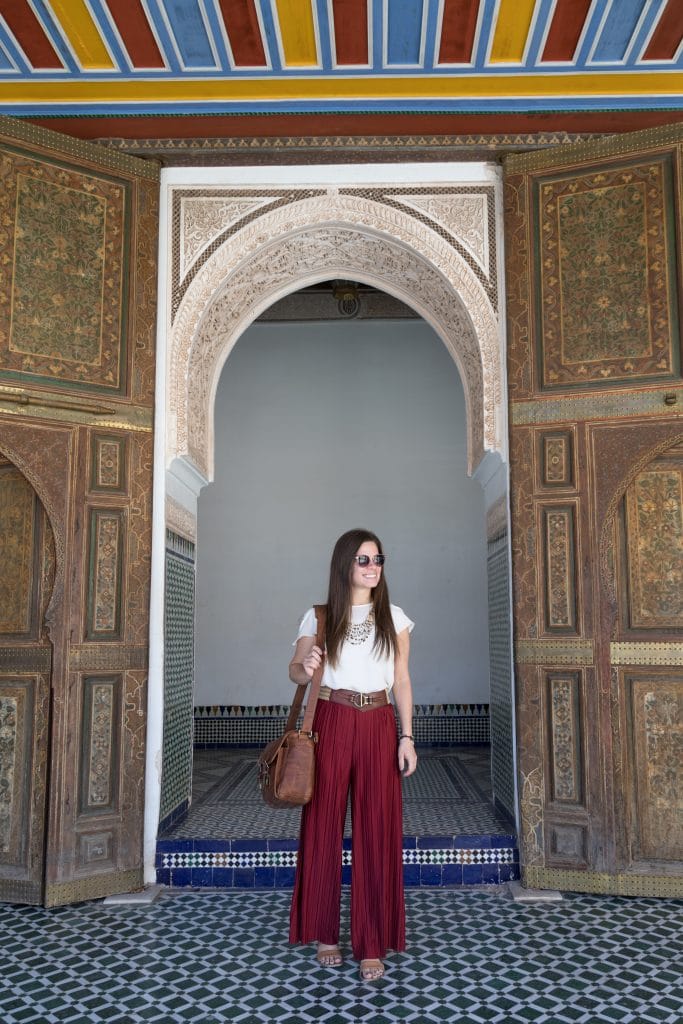 A girl in red pants and a white top standing in a doorway in Morocco.