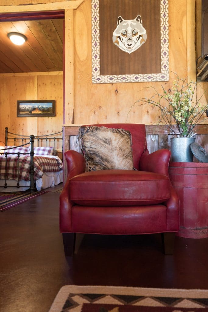 A red chair and wolf artwork outside a bedroom at Maison Tetonia.