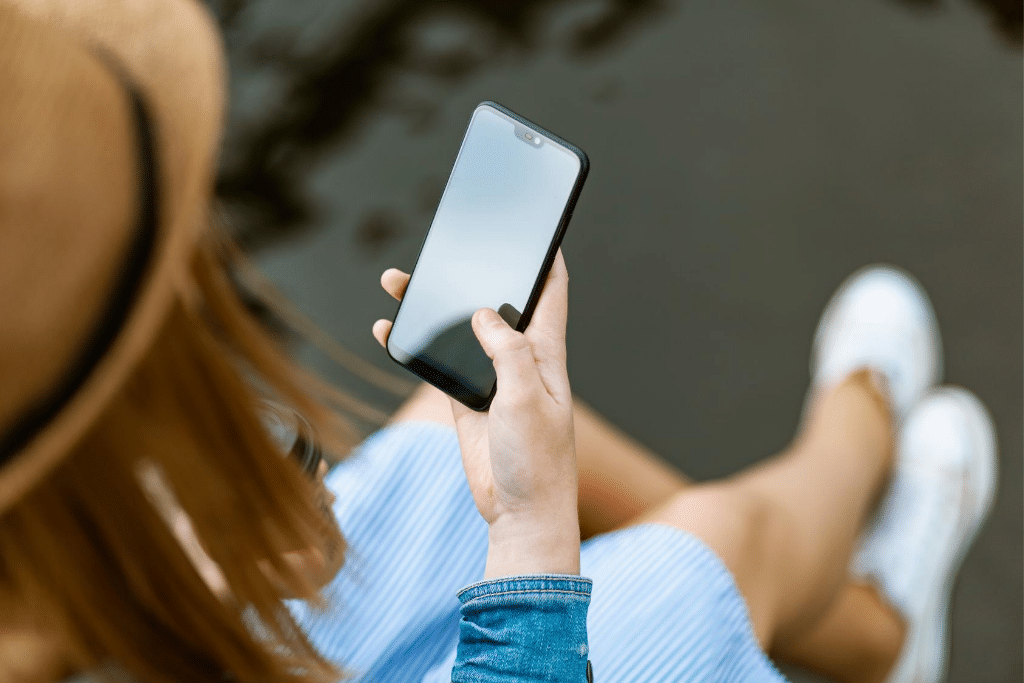 A girl in a hat holding a cell phone.