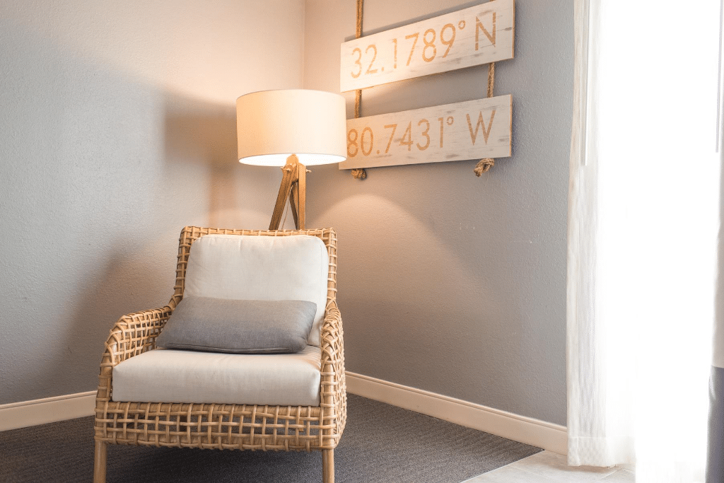 A lamp and a chair with wall art.
