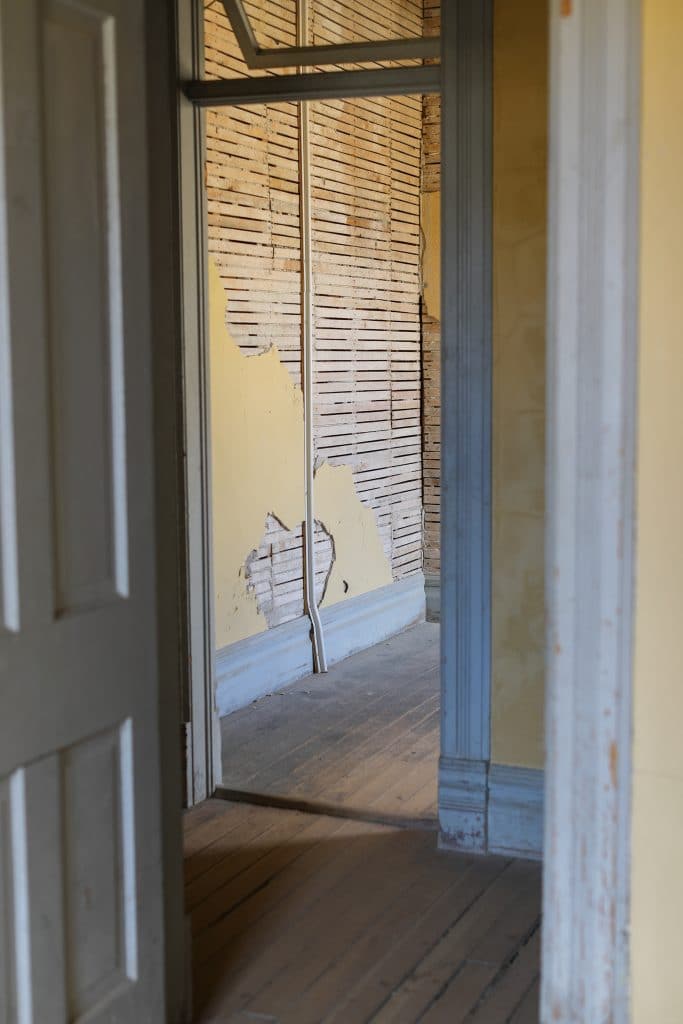 A blue doorway with yellow, decaying walls.
