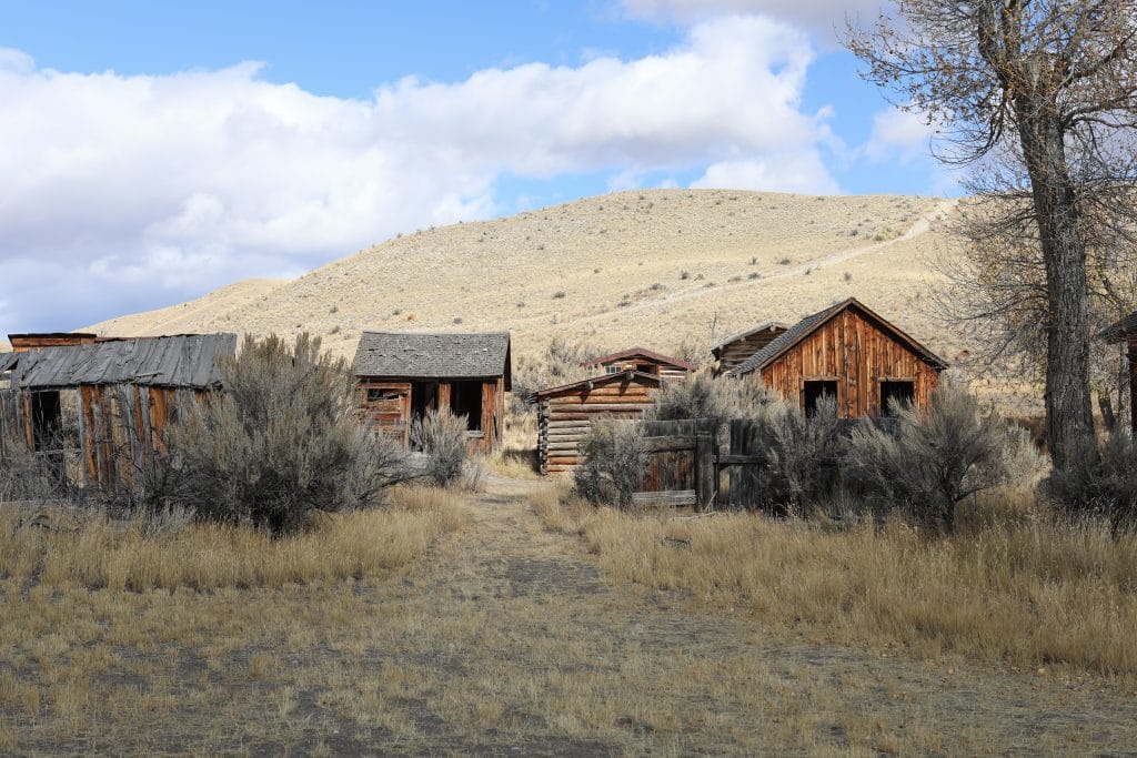 Wooden cabins along batchelor row. Read on for more history of the ghost town in Bannack Montana.