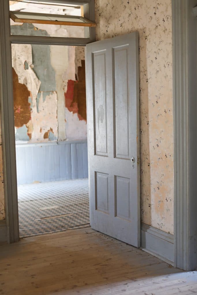 A blue door and layers of wallpaper in an old cabin.