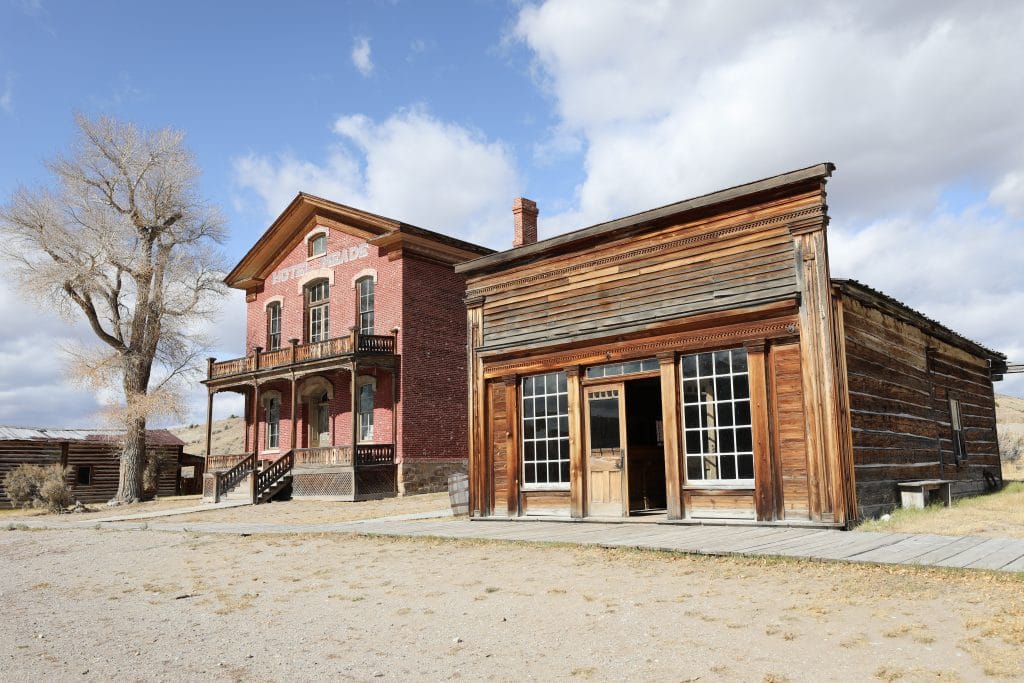 A brick building next to a wooden building in the ghost town of Bannack, Montana.