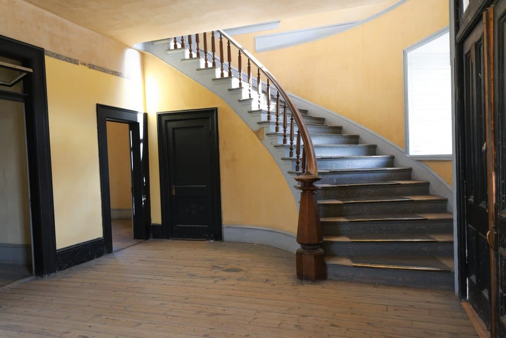 A blue and yellow spiral staircase near black doors in the old court house of Bannack, Montana.
