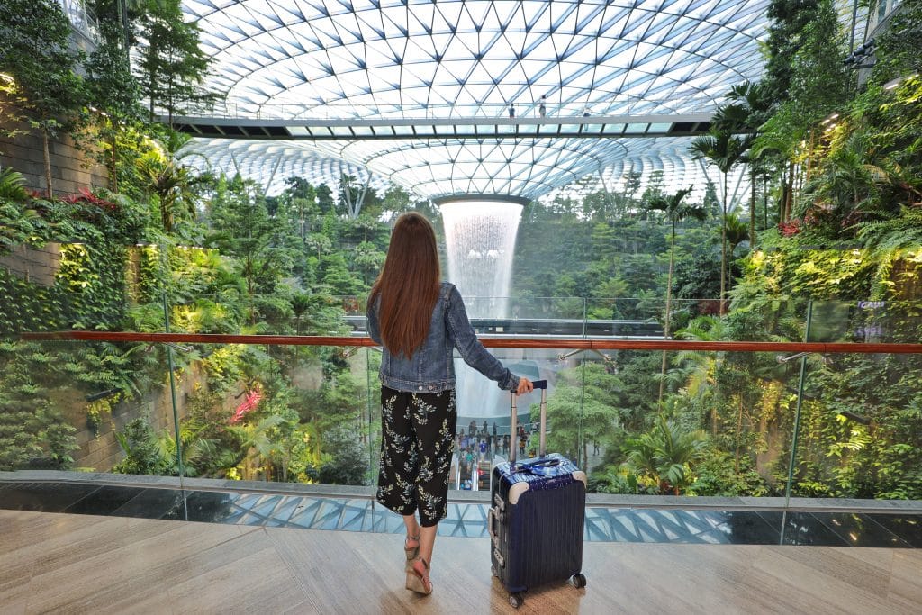 A girl standing near greenery and an indoor waterfall at the Changi Airport. #changiairport #singaporeairport