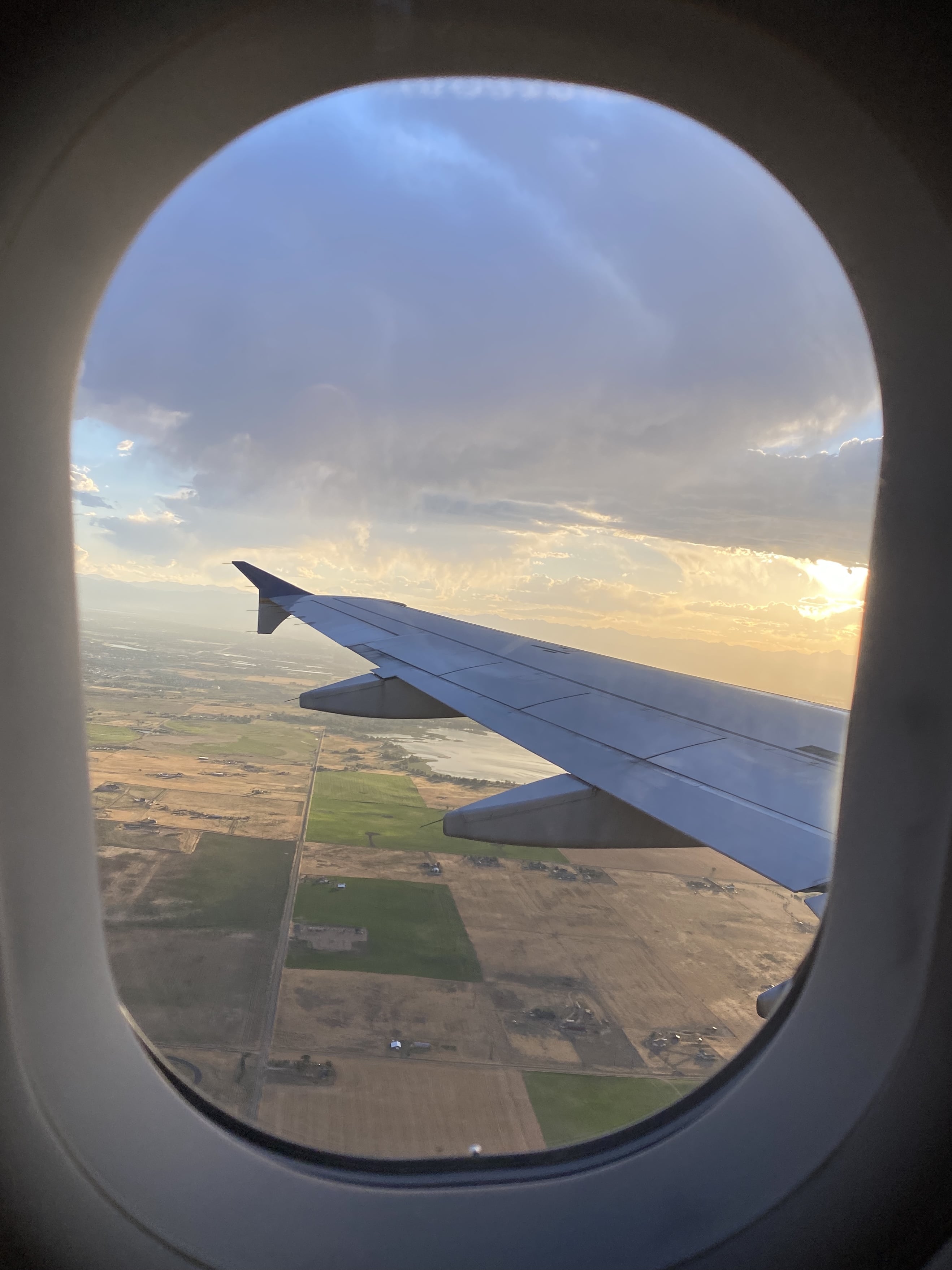 Looking out a plane window at the wing over fields at sunset. The thrill of flying is just another reason to be thankful for travel.