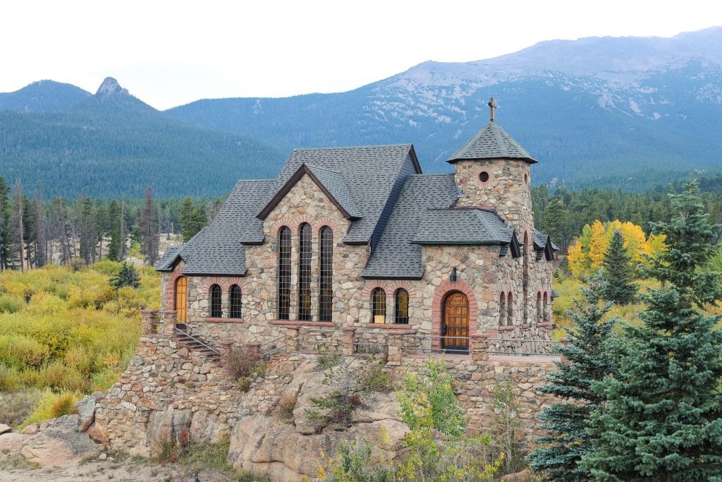 A stone church surrounded by yellow aspen trees with mountains in the background. One of the most picturesque moments of 2020.