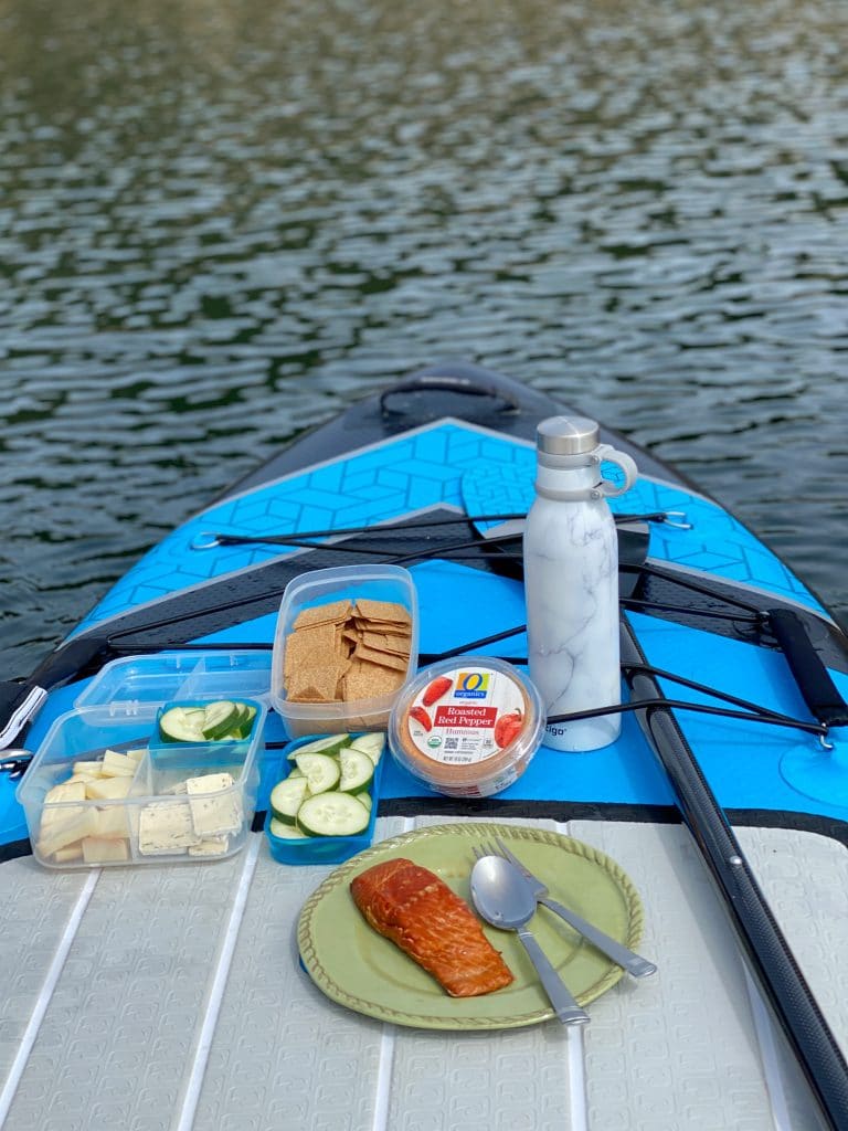 The front of a paddleboard with food displayed on it. A delicious pandemic appropriate adventure!