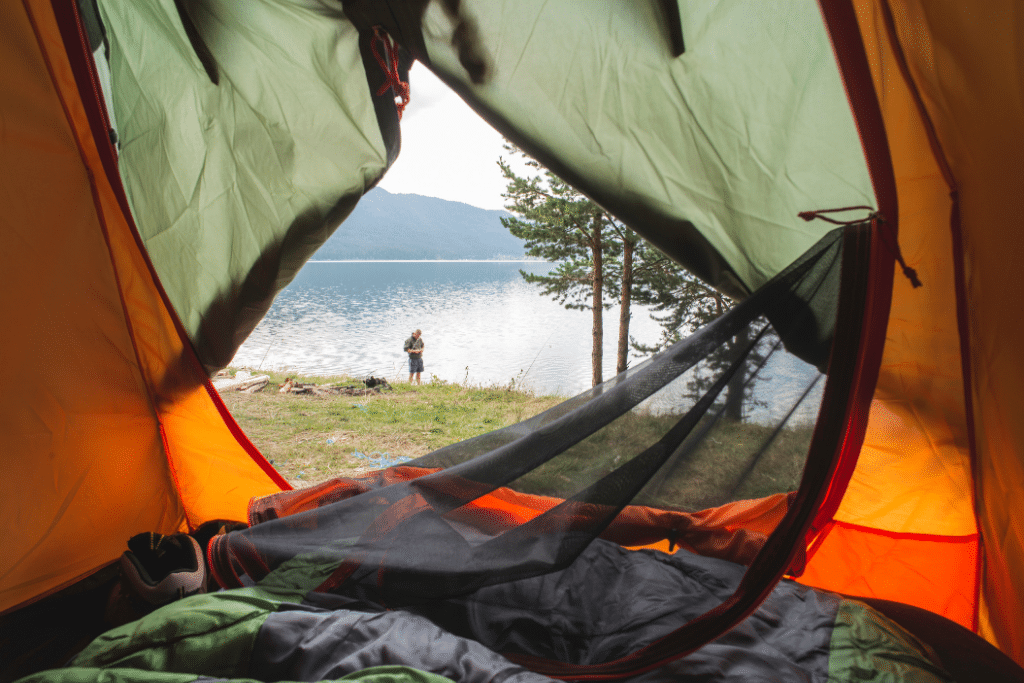 Looking out of a tent door at a man standing along a lake. A fun, outdoorsy pandemic appropriate adventure.