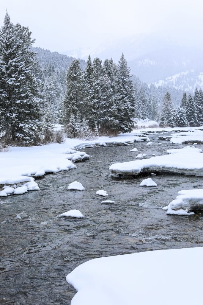 A snowy river with mountains in the background. #320guestranch