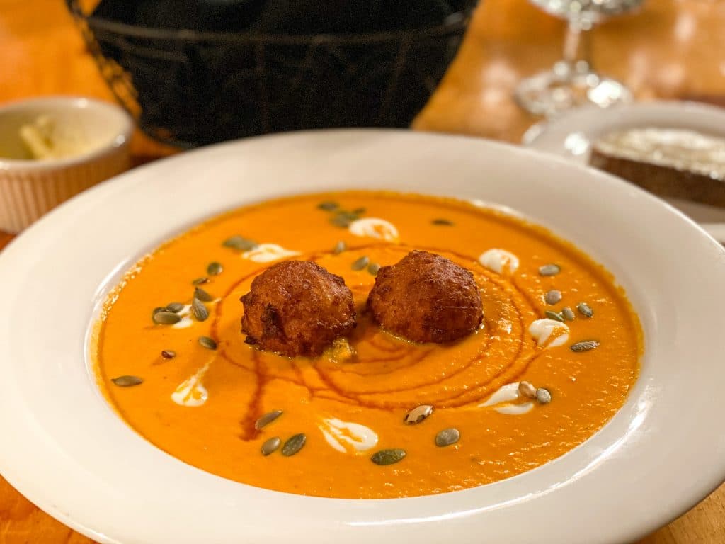 A delicious bowl of squash soup with two corn fritter balls and pepita seeds. #320guestranch