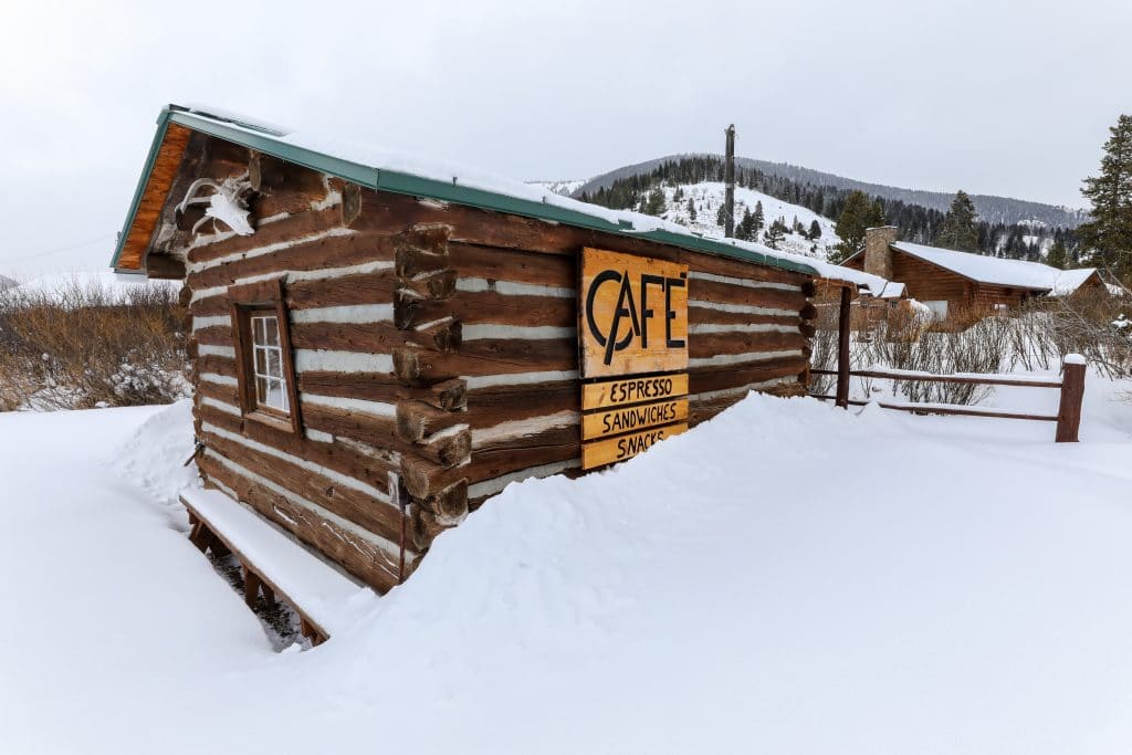 A snow-covered log cabin cafe at the 320 Guest Ranch. #320guestranch