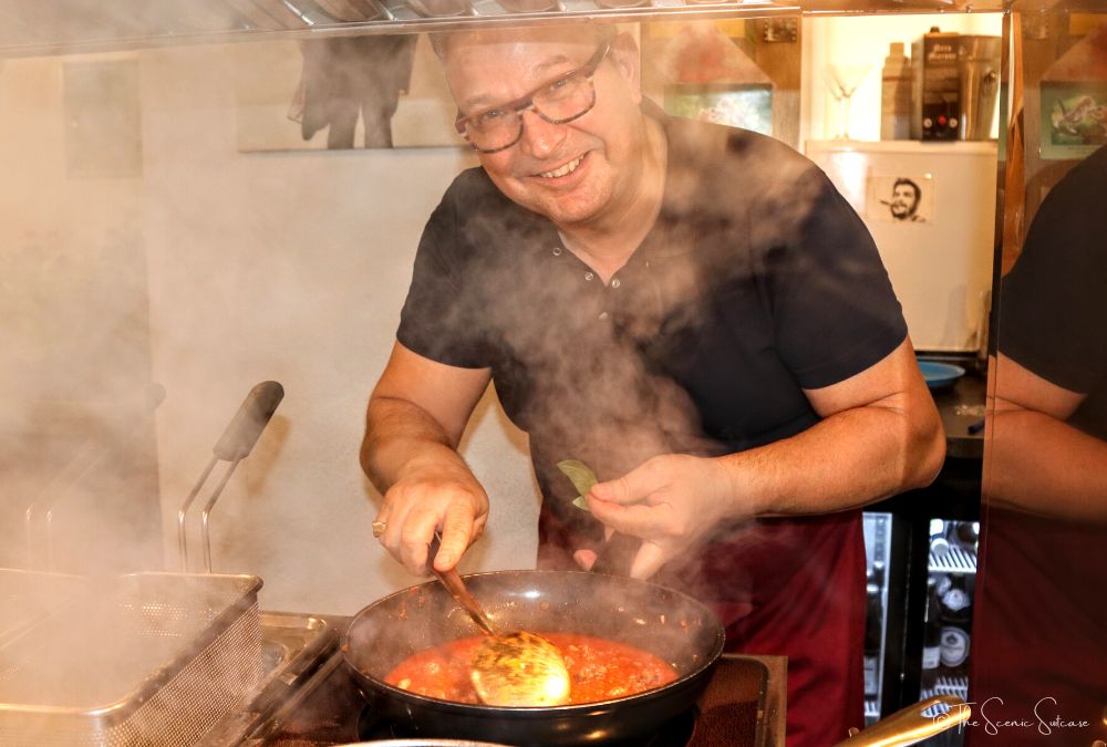 A man cooking pasta sauce in a small Italian restaurant.