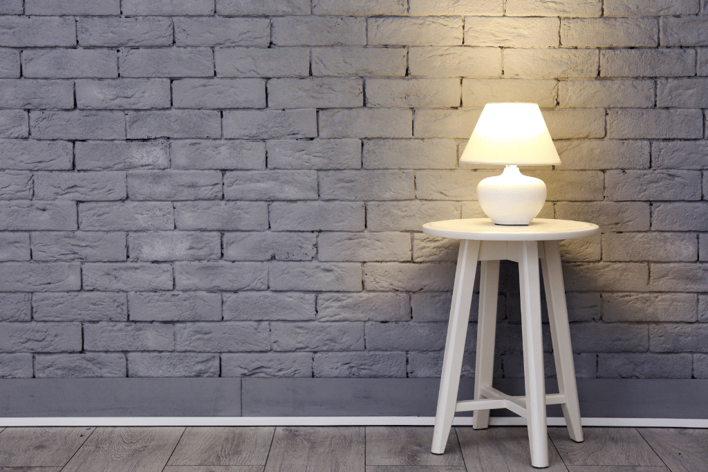 A lamp against a grey brick wall. Learn 5 ways to keep your home safe while you're away from home and traveling the world. From how to thwart theives to security systems.