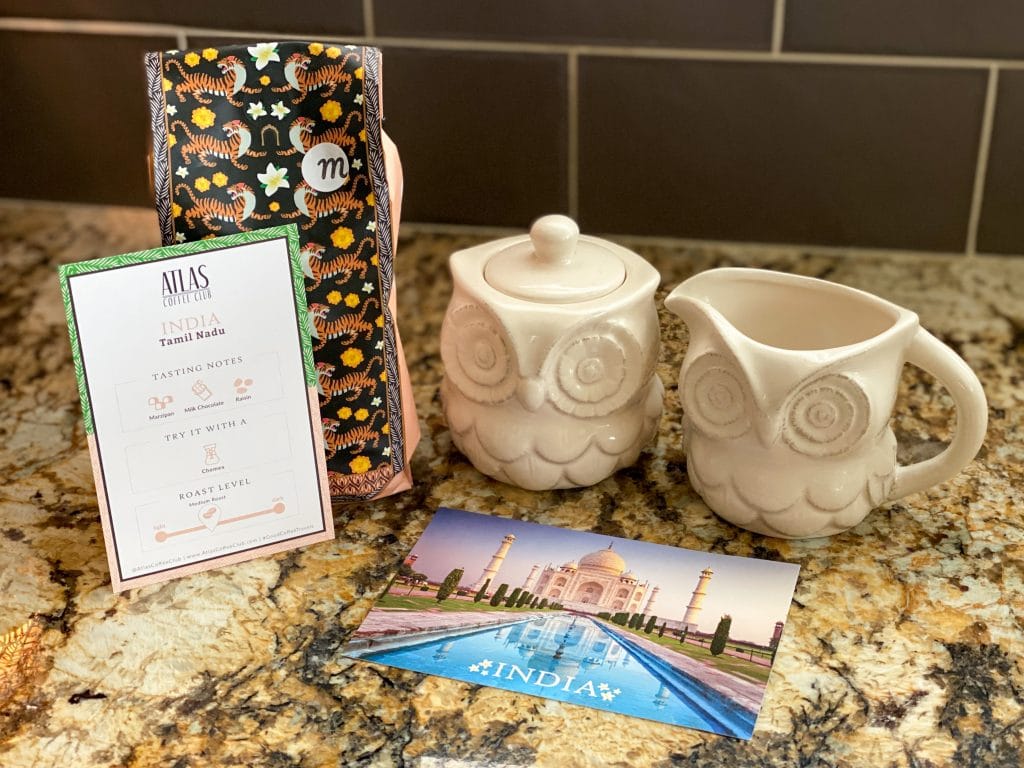 A bag of coffee beans, a postcard, and owl cream & sugar containers.